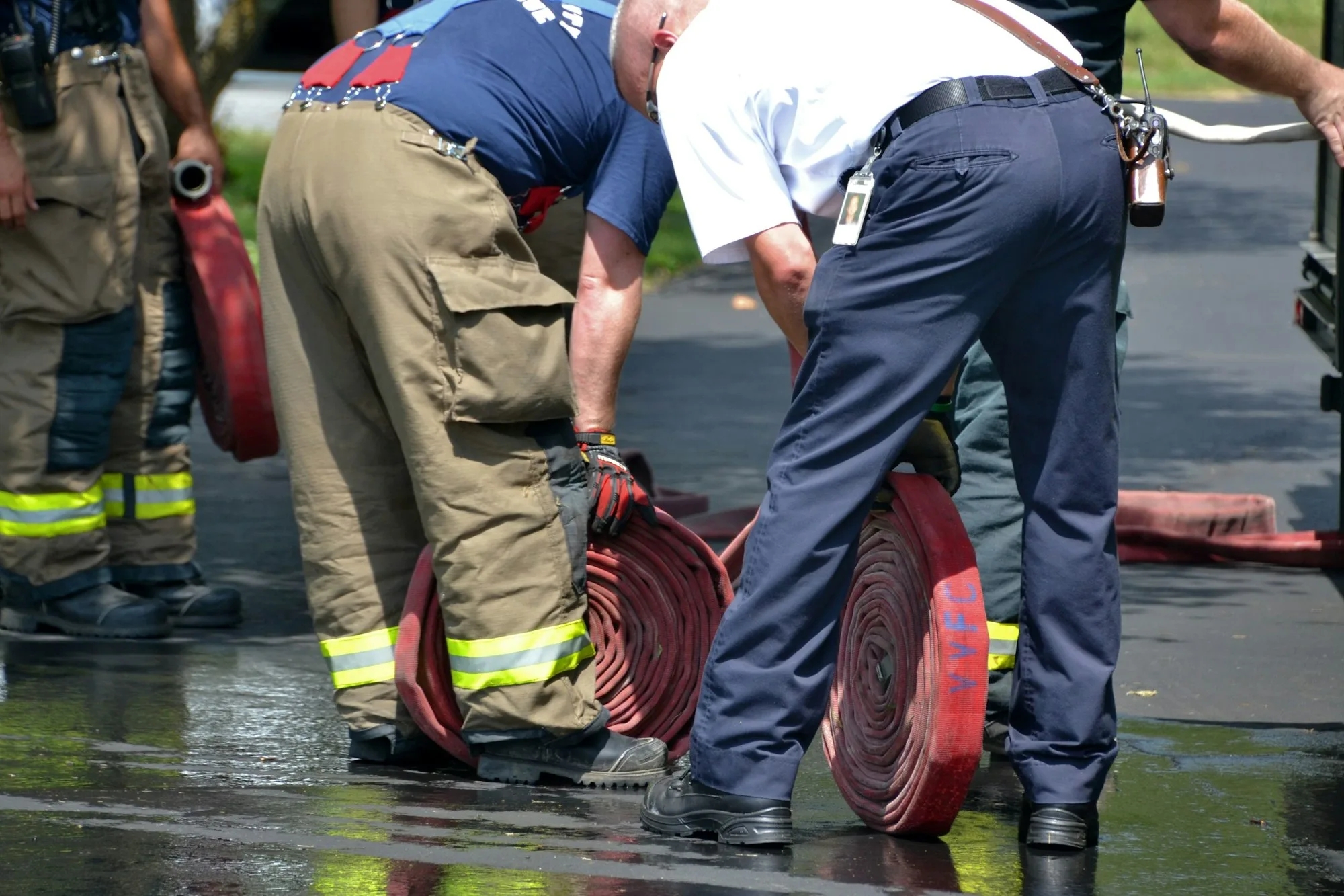 firemen rolling up fire hoses on the wet pavement after fighting a fire firefighters jpg